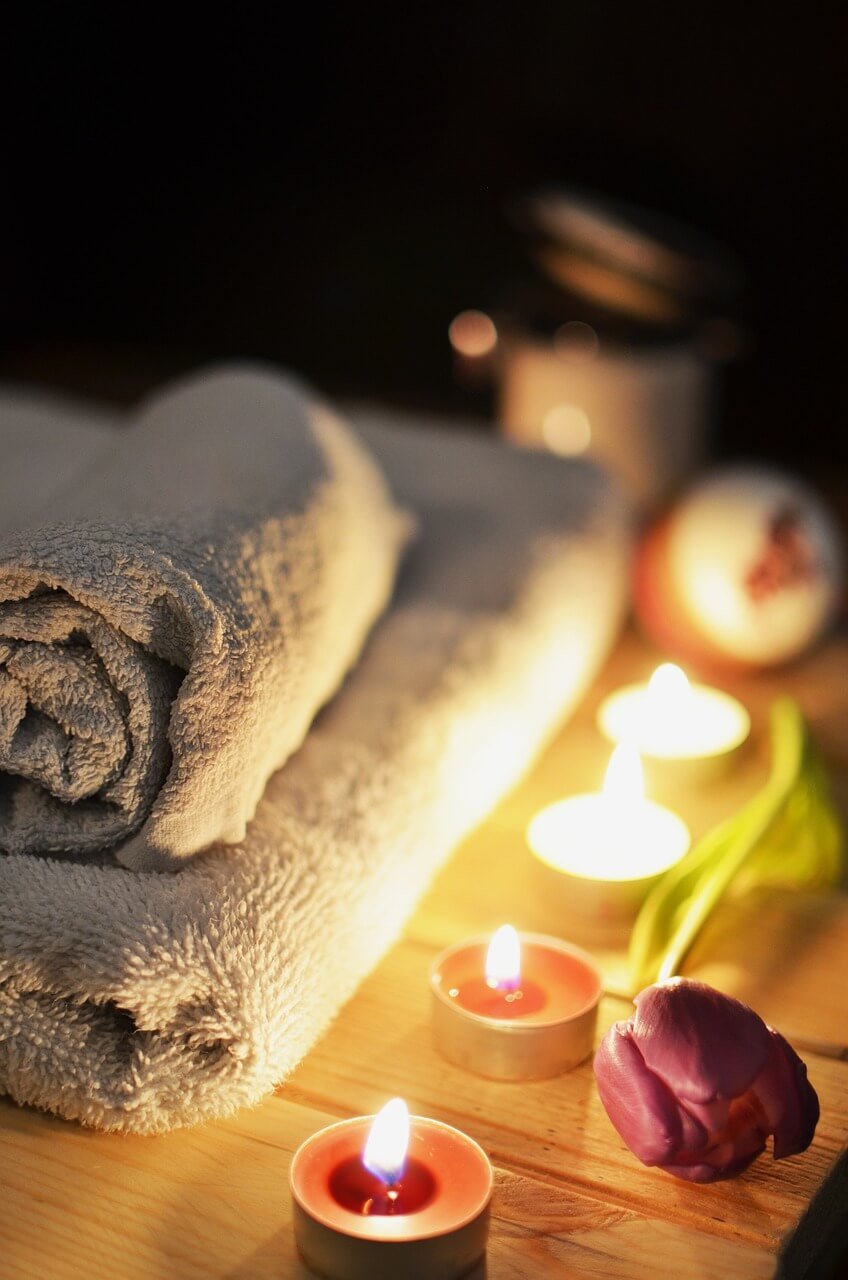 Toalla con velas y flor en ambiente íntimo de hotel