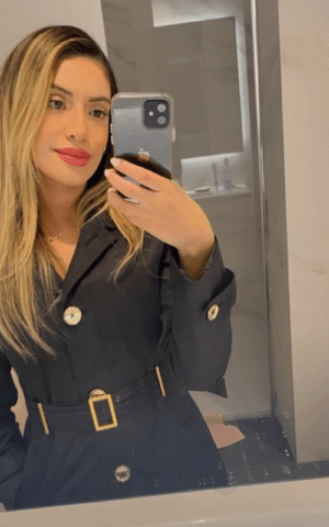 Lilian escort brasileña en Madrid tomándose un selfie con abrigo negro y labios rojos