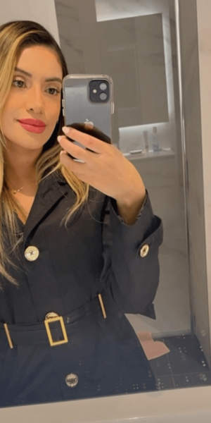 Lilian escort brasileña en Madrid tomándose un selfie con abrigo negro y labios rojos