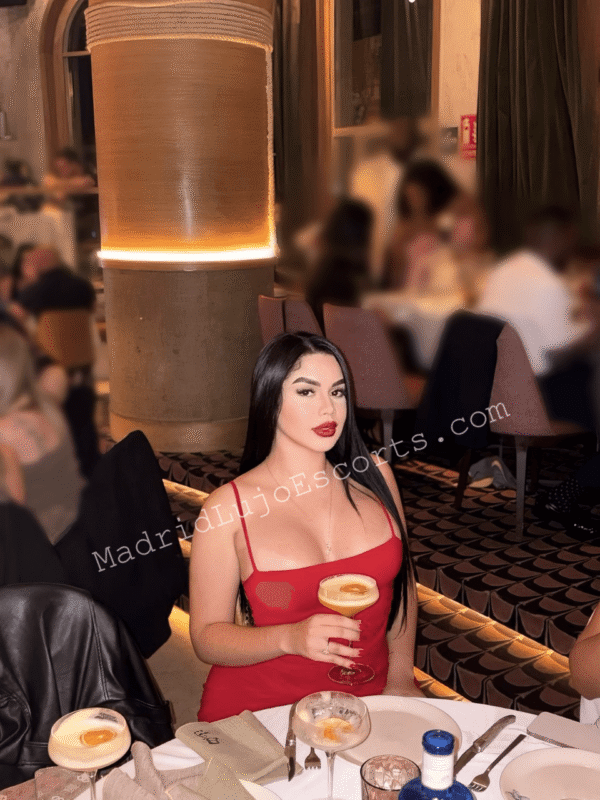 Nahomy con vestido rojo y copa en restaurante elegante