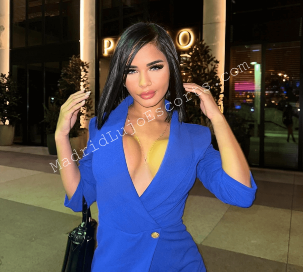 Sabrina con blazer azul, escote profundo y mirada intensa