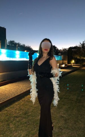 Andrea escort española de lujo en Madrid con vestido largo negro y estola blanca al atardecer
