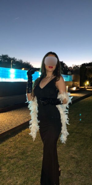 Andrea escort española de lujo en Madrid con vestido largo negro y estola blanca al atardecer
