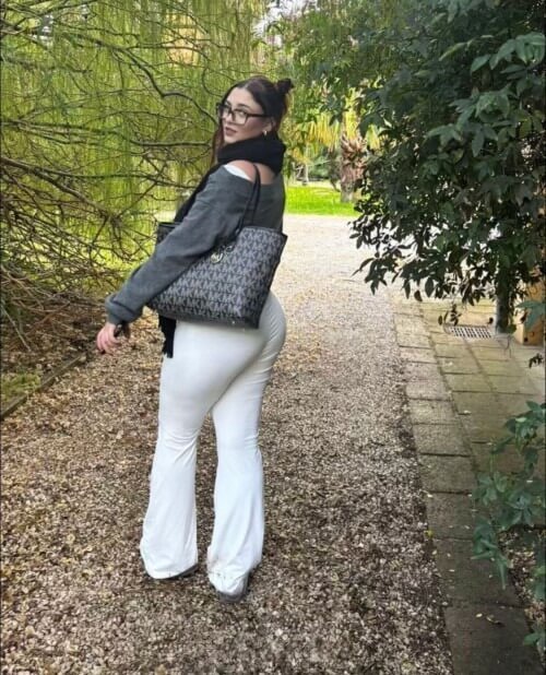 Martina escort española de lujo en Maadrid caminando por el parque con pantalón blanco ajustado