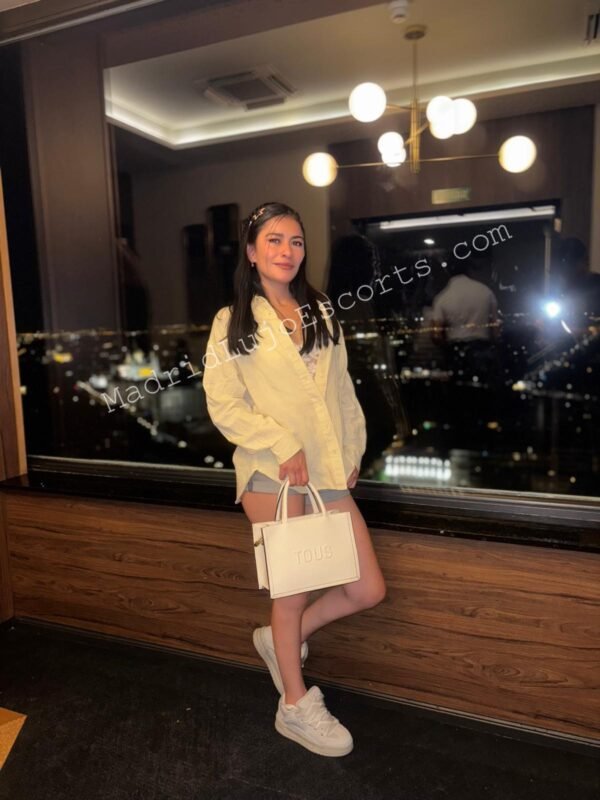 Krissty con vestido beige en terraza con vistas nocturnas