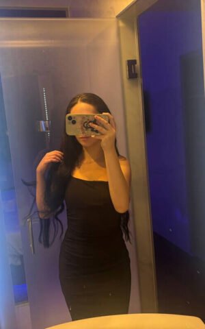 Angy, escort española de lujo en Madrid con vestido negro elegante frente al espejo