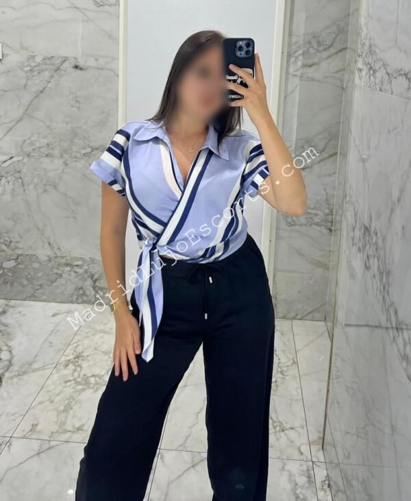 Belén frente al espejo con blusa anudada y pantalón negro