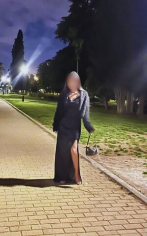 Sarita, escort de lujo en Madrid con vestido negro elegante en un paseo nocturno por Madrid