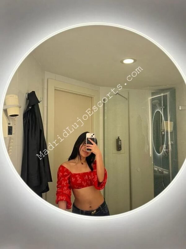 Sarita con top rojo sensual en selfie frente al espejo