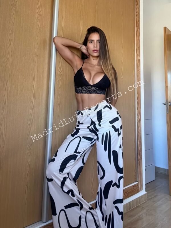 Nastassia escort venezolana en Madrid con top negro y pantalón blanco estampado