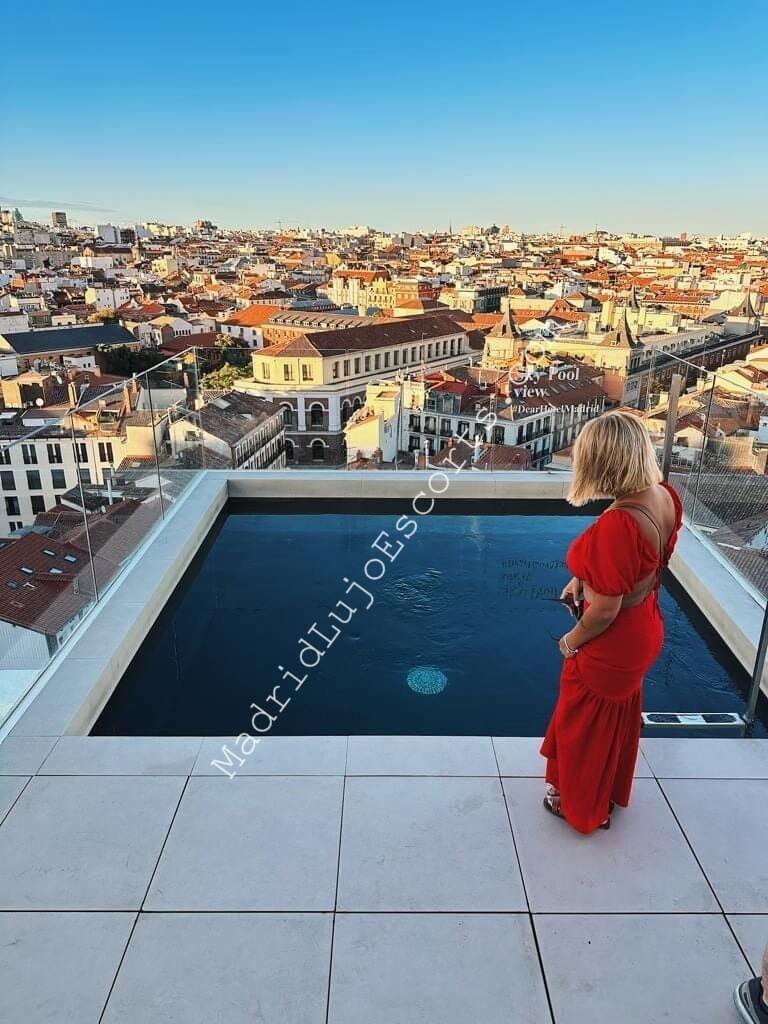 Sara escort española en Madrid con vestido rojo en una azotea con vistas a la ciudad
