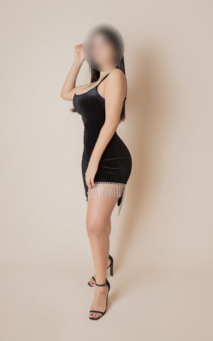 Betsi, escort Madrid con vestido negro corto posando de perfil