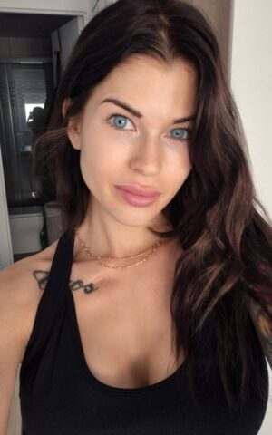 Sarah escort en Madrid posando con top negro en un selfie interior