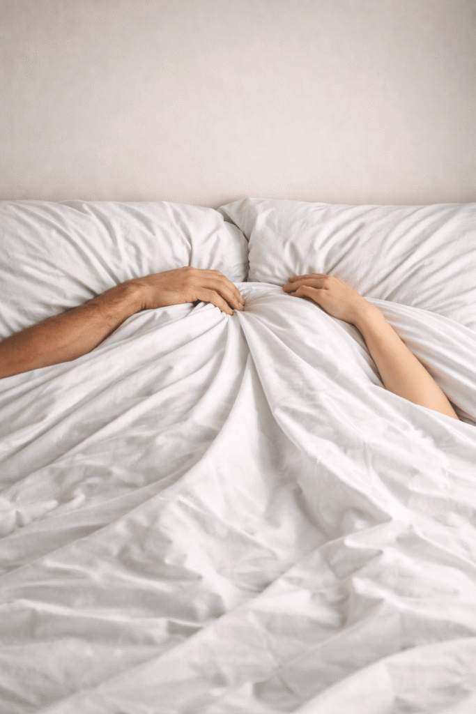 Persona en la cama bajo sábanas evocando el significado del griego sexual