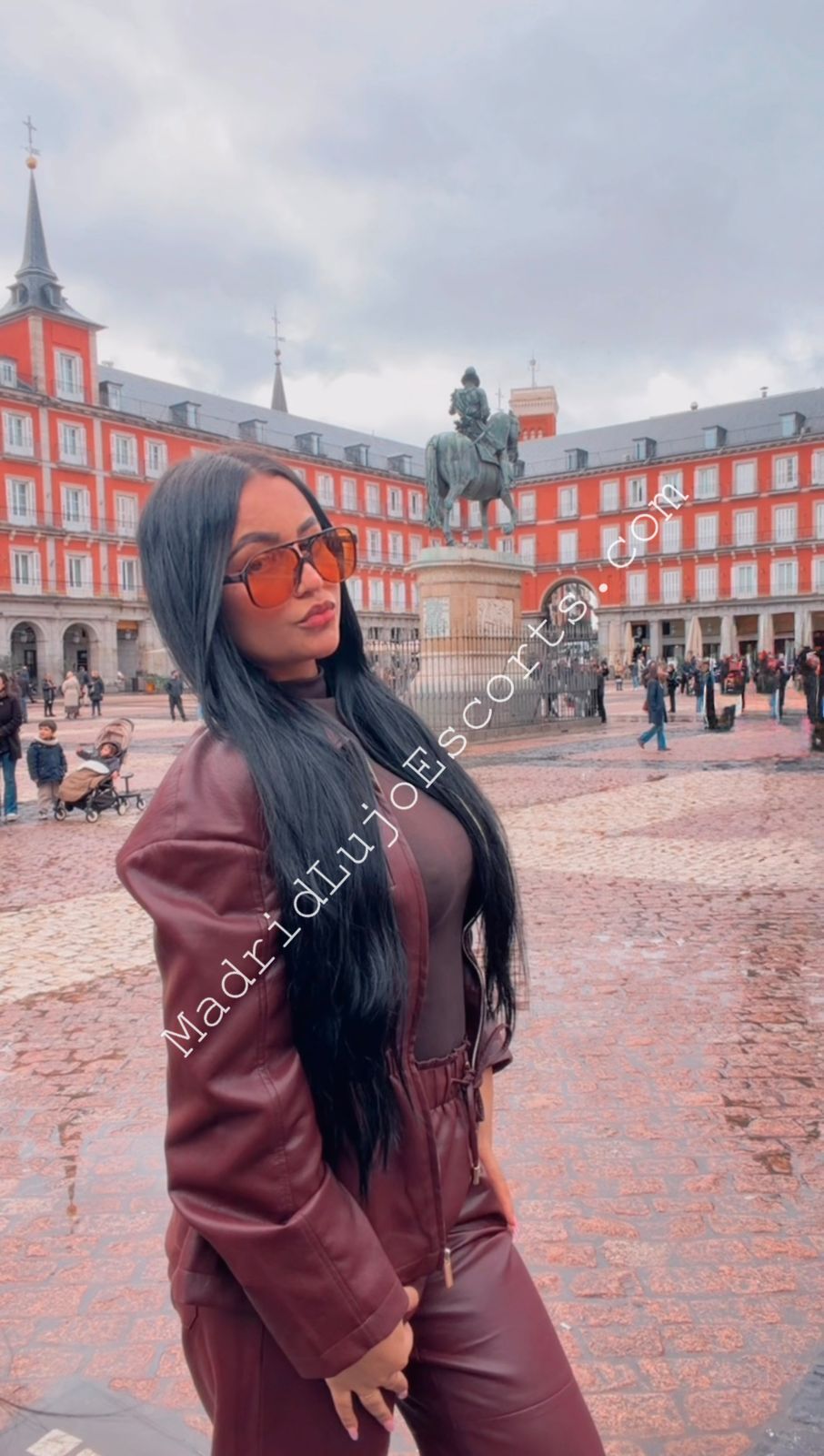 Aline, escort Madrid posando en una plaza céntrica con outfit marrón